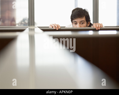 Male office worker peeping over partition wall Stock Photo