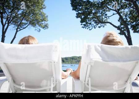 Couple holding hands and lying on lounge chairs Stock Photo