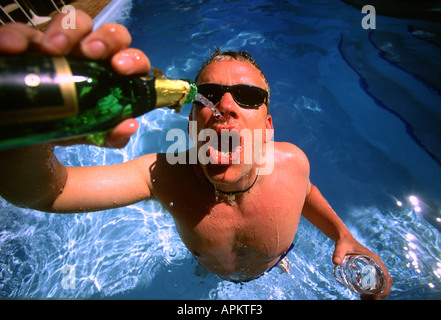Man drinking champagne in a swimming pool Stock Photo