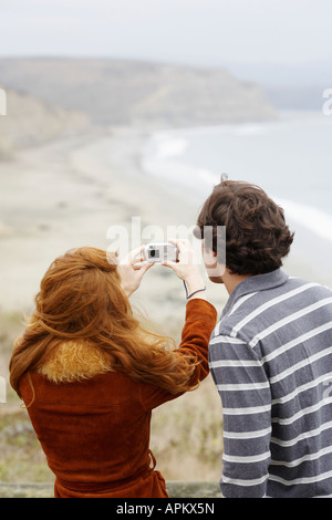 Couple taking photographs at beach (rear view) Stock Photo