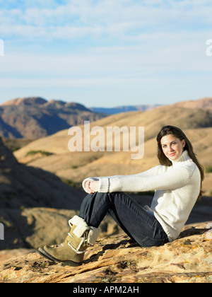 young woman sitting on the rocky seashore Stock Photo - Alamy
