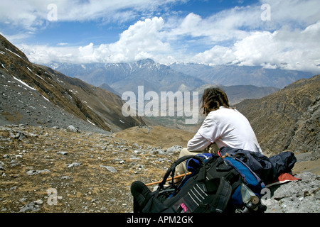 Trekker resting after the Thorung La pass (5416m). Looking at the Muktinath valley in Mustang. Annapurna circuit trail. Nepal Stock Photo