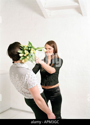 Woman throwing bunch of flowers at man Stock Photo