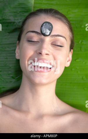 Happy young woman receiving hot stone therapy, directly above Stock Photo