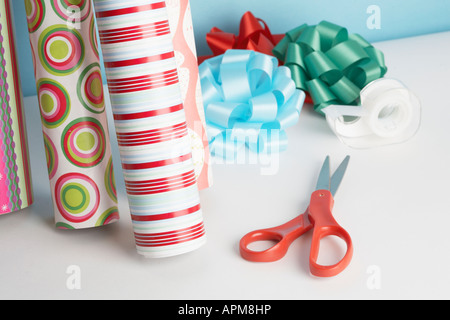 Rolls of colorful wrapping paper, scissors and ribbons on white