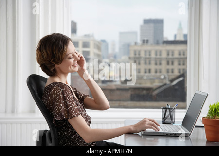 Businesswoman talking on the phone and using laptop Stock Photo