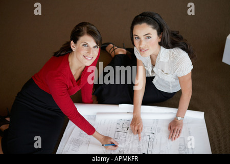 Two businesswomen examining blueprints (portrait, high angle view) Stock Photo