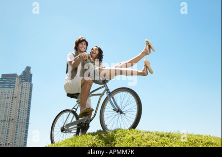 Young couple cycling, woman balancing on handlebar Stock Photo
