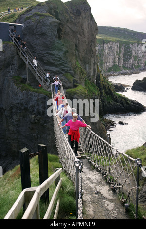 Tourists cross the famous suspended rope bridge at Carrick a Rede, north Antrim coast Northern Ireland GB UK