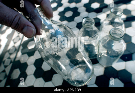 Four empty one pint milk bottles being collected on a traditional doorstep Stock Photo