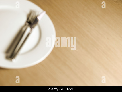 Empty clean dinner plate with knife and fork on tabletop Stock Photo