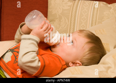 baby boy holding feeding bottle feeding himself milk ten months old Stock Photo