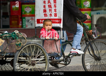 Baby rides in bicycle wagon, Yueqing, Zhejiang Province, China Stock Photo