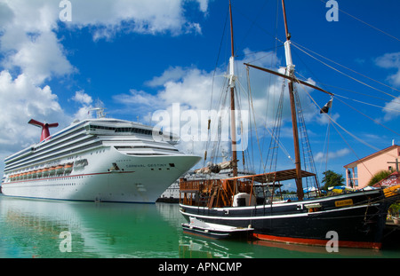 New Carnival Destiny cruise ship at port contrasting with old sailboat called Black Swan in St Johns in Antigus in the Caribbean Stock Photo