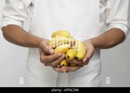 Chef holding bunches of bananas (mid section) Stock Photo