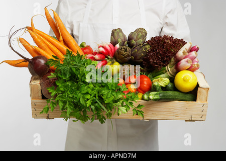 Chef holding box of vegetables (mid section) Stock Photo