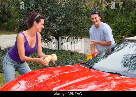 Affluent young Couple in their 30s having fun washing red car Stock Photo