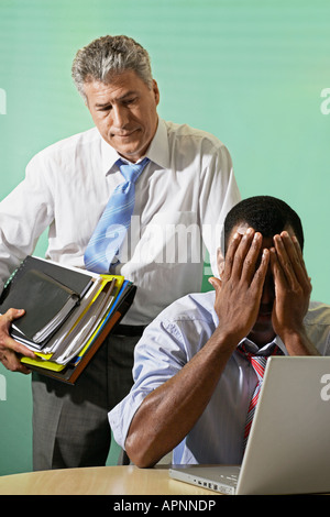 Two Serious Businessmen, Young Man with Head in Hands Stock Photo