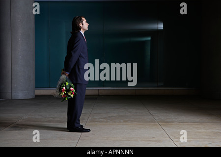 Businessman Standing with Bunch of Flowers Behind Back Stock Photo