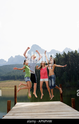 Four Teenagers Jumping on Jetty Stock Photo