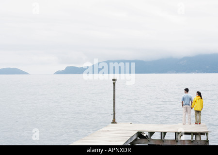 Young couple standing on jetty and looking at view Stock Photo
