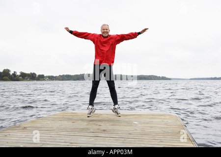 Senior man jumping on jetty Stock Photo