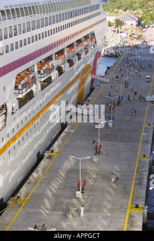 Passengers walk along the pier beside the Ocean Village Two cruise liner docked at the Port of St. Maarten Stock Photo