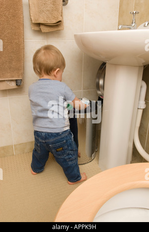Baby boy eleven months old playing with rubbish bin in bathroom Stock Photo