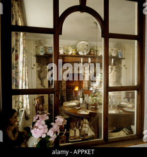 View through cottage window into dining room with open fireplace Stock Photo