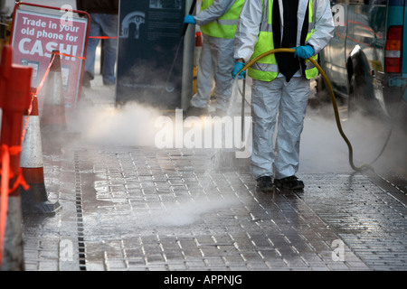 local council workers in hi vis vests powerhose wash chewing gum off city streets in Belfast Northern Ireland UK Stock Photo