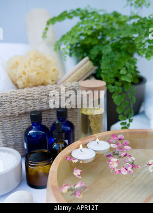 Spa bathroom setting: aromatherapy oils, cotton wall balls, natural sponge, wooden bowl filled with water and floating petal Stock Photo