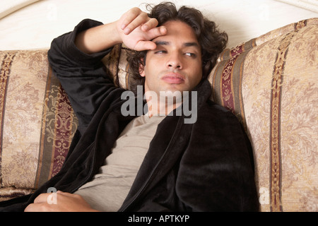 Hispanic man sitting on bed Stock Photo
