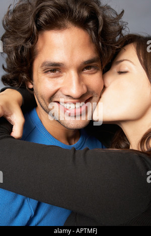 Hispanic woman hugging and kissing boyfriend Stock Photo