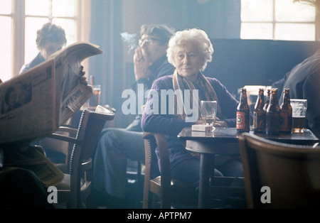 People drinking in pubs bars smokey bar with lady sitting at table in the middle Stock Photo