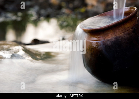 Filling an Indian Clay pot with fresh clean water at a hand water pump in the indian countryside. Andhra Pradesh, India Stock Photo