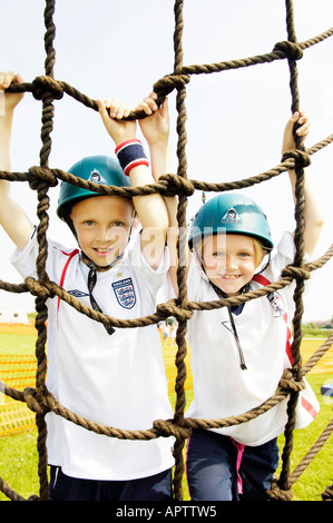 Boy and girl climbing on army assault course cargo net Stock Photo