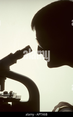 silhouette of lab technician looking through microscope Stock Photo