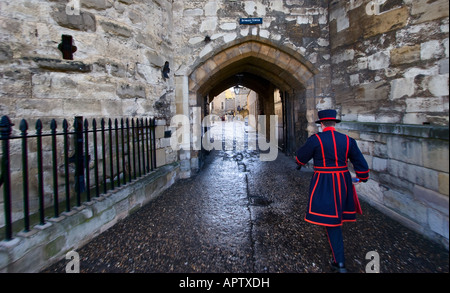 A Yeoman Warder walks beneath Byward Tower at the Tower of London in London England Stock Photo