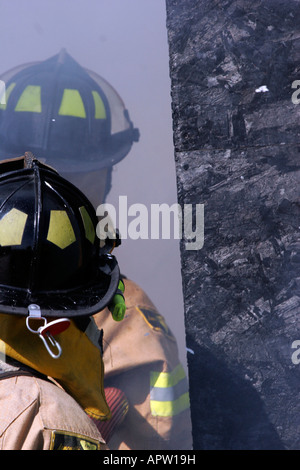 Two firefighters extinguishing a structure fire Stock Photo