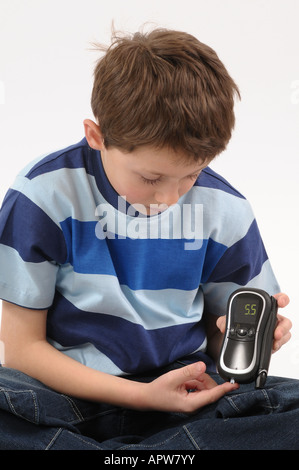 Young diabetic boy doing blood glucose level test. 2008 device Stock Photo