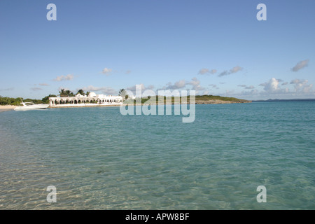 Beachside pavillion on the Caribbean island of Anguilla with crystal clear sea and clue sky with a motor boat moored on the beac Stock Photo