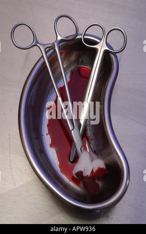 used surgical instruments scissors with blood on them in a kidney bowl Stock Photo