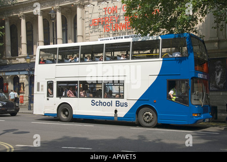Young children looking out of window of double decker blue & white school bus transport in Charing Cross Road City of Westminster London England UK Stock Photo