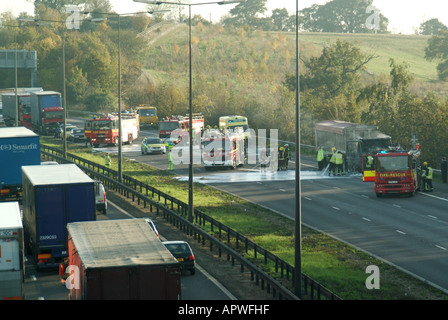 View from above fire brigade ambulance & police emergency services blocking motorway attending lorry truck fire with traffic queues Essex England  UK Stock Photo