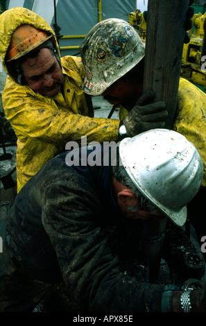 roughnecks changing a drill bit on the floor of an oil rig Stock Photo