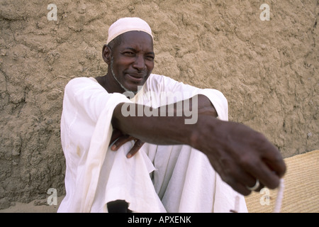 Timbuktu man sitting on a grass mat leaning against a mud wall Stock Photo