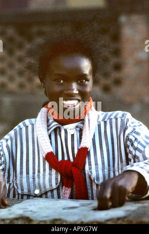 Smiling young African woman wearing a striped shirt and red and white scarf Stock Photo