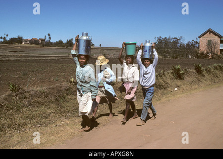 Group of woman carrying canisters of water on their heads Stock Photo