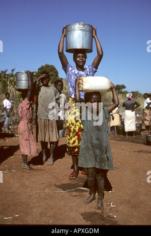 Group of women and a young girl carrying water canisters on their heads Stock Photo