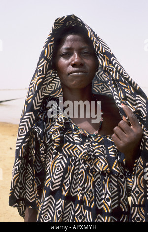 Peul woman wearing traditional gold and black printed dress and head covering Stock Photo